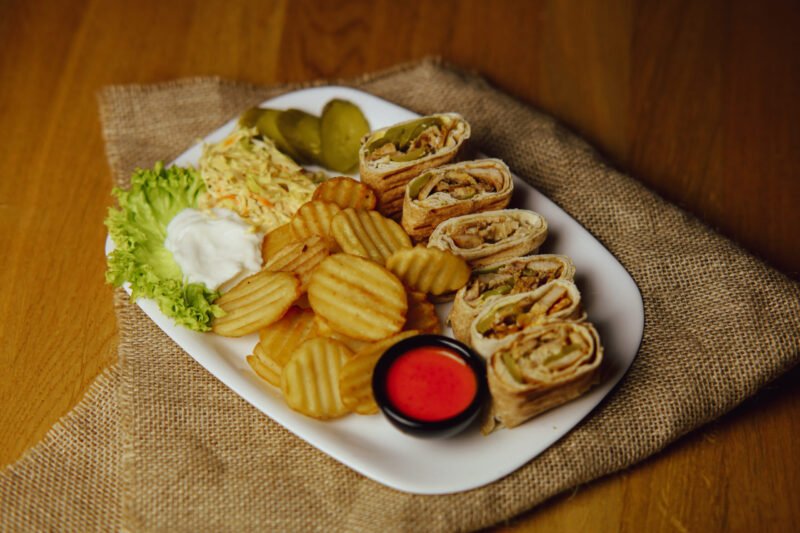 image of Bread filled with chicken shawarma, cheese, pickle, garlic sauce, and fries on the side.