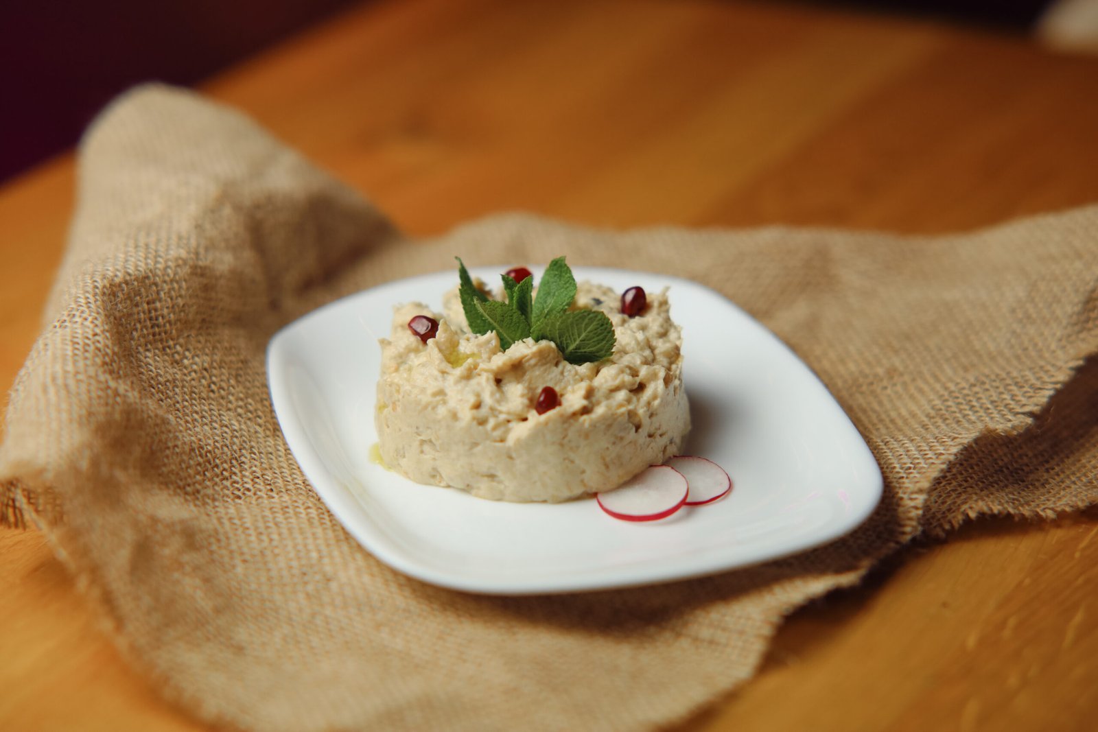 mutabal image Grilled eggplant, tahini, pomegranate, lemon juice, pomegranate sauce, olive oil, and Lebanese bread.