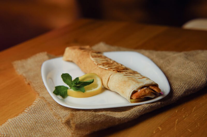 chicken shoarma sandwich image Saj bread with chicken shawarma, pickle, garlic sauce, pomegranate sauce.